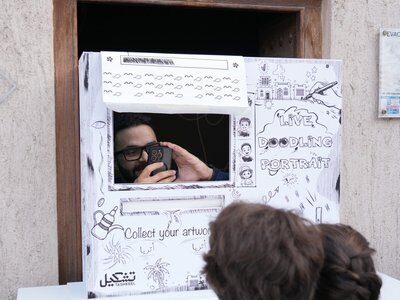Children watching a live doodle portrait artist at a window booth – Live Doodle