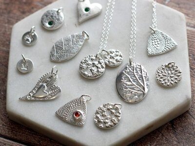 Handmade silver clay pendants on a marble tile – Sculpted in Silver workshop